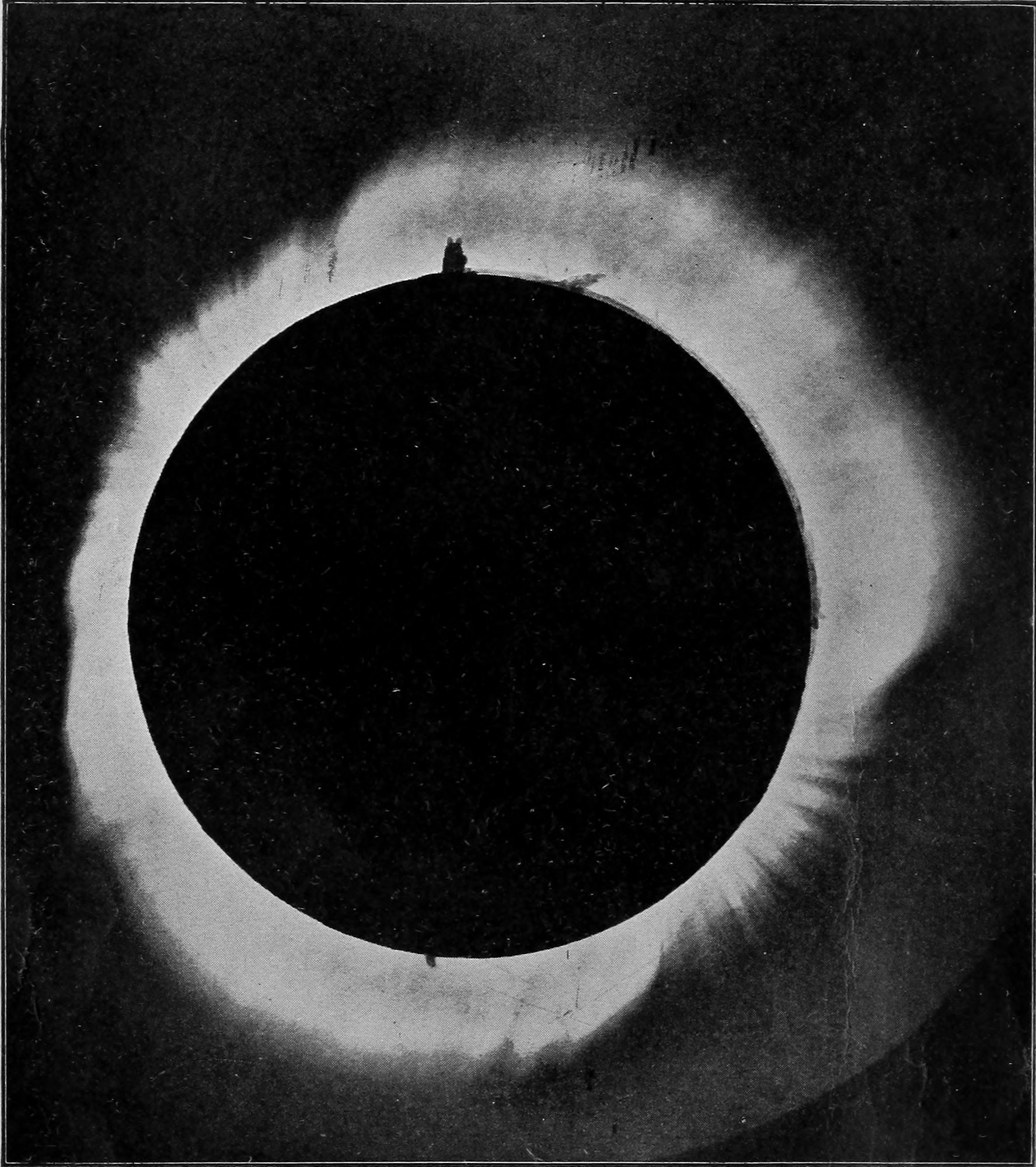 Total Eclipse of the Sun of May 29, 1900. Photographed by the party of the Smithsonian Institution. — A photograph of the moon's black disk covering the sun, ringed by the bright corona, which streams out farthest at the sides; small dark prominences stand on the top and bottom edges.