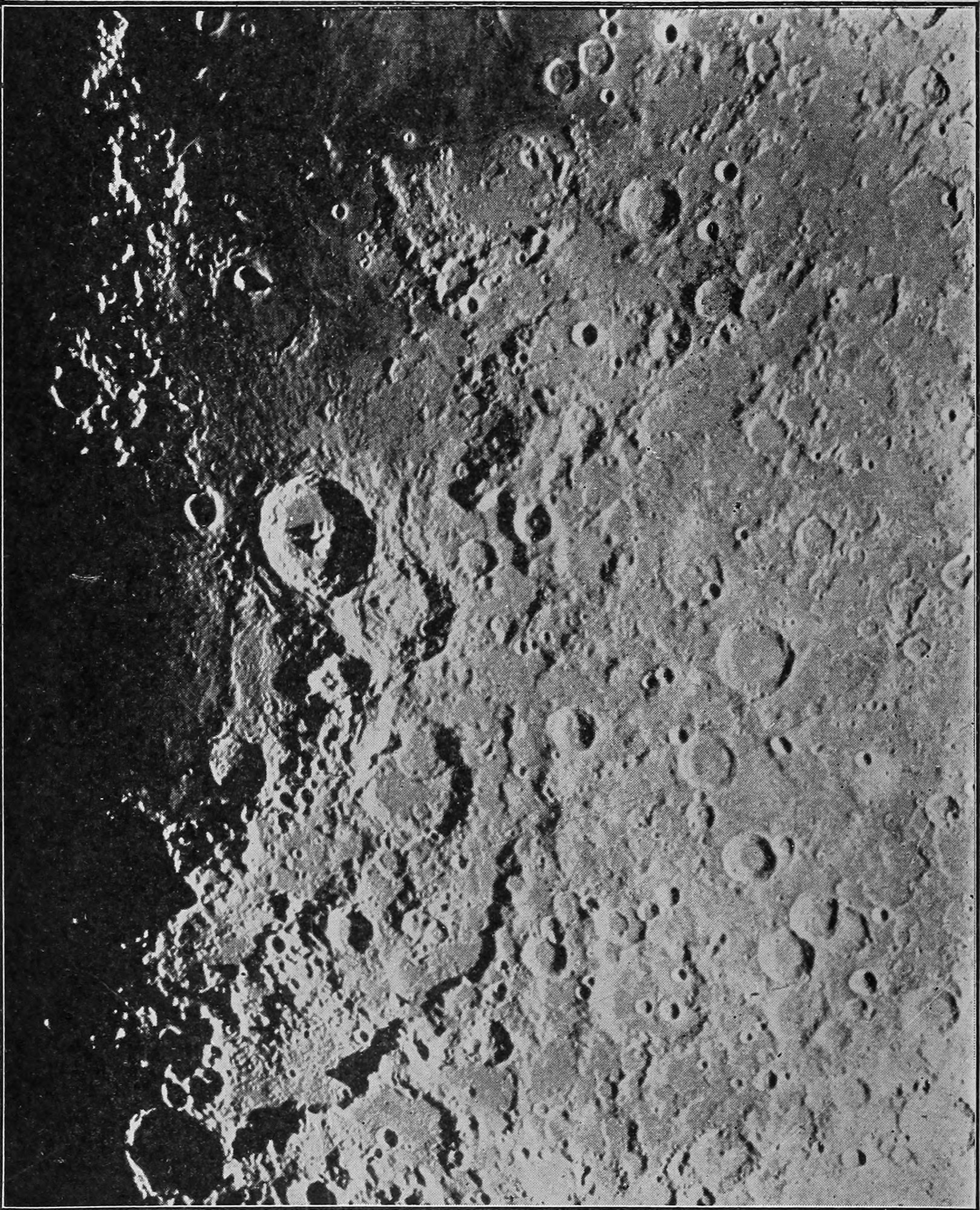 Fig. 20.—Mountainous Surface of the Moon. — A photograph of a stretch of the moon near the line between light and dark, crowded with round craters and ringed mountains whose shadows fall black on the left.
