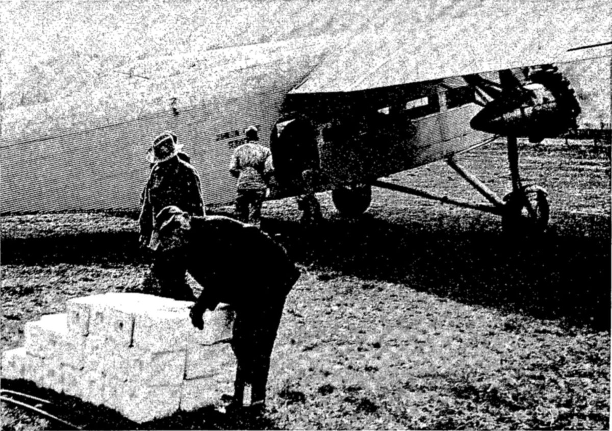 [?] their importance in game inventories, airplanes have many other uses in game management. Here [?]nd blocks of salt are being loaded aboard a plane, which will carry them over mountain ranges, drop[?]em on summer feeding grounds of elk and other game animals. The purpose is to lure the game onto [?]mer ranges earlier in the spring and hold them later in the fall, thus saving winter forage, of which in [?]calities there is a critical shortage. — Men in hats stand beside a large high-winged airplane parked on a grass field; one bends over a stack of white blocks on the ground in the foreground.