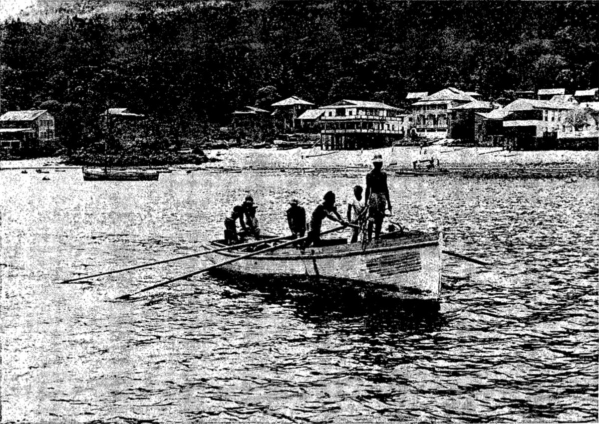 Divers at work during the pearl oyster survey off the coast of Panama — An open boat with long oars carries several men, one standing at the stern, across a bay, with houses along a beach and forested hills behind.