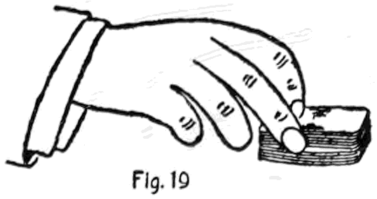 Fig. 19. — A hand seizing the ends of the deck as it lies on the table, cutting at the opening left by the crimp.
