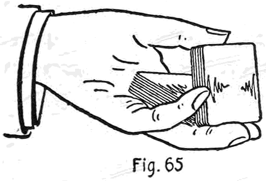 Fig. 65. — The left hand holds the deck face down with the thumb along one side; the lower portion has been released and lies tilted in the palm while the thumb still supports the upper portion.