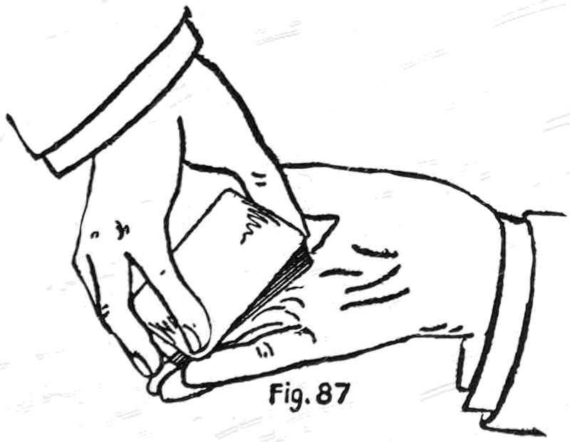 Fig. 87. — The Sixth Method: the left hand holds the deck by the ends, face to the company, and the little fingertips of both hands meet at the lower corner, clipping the pushed-over card between them.