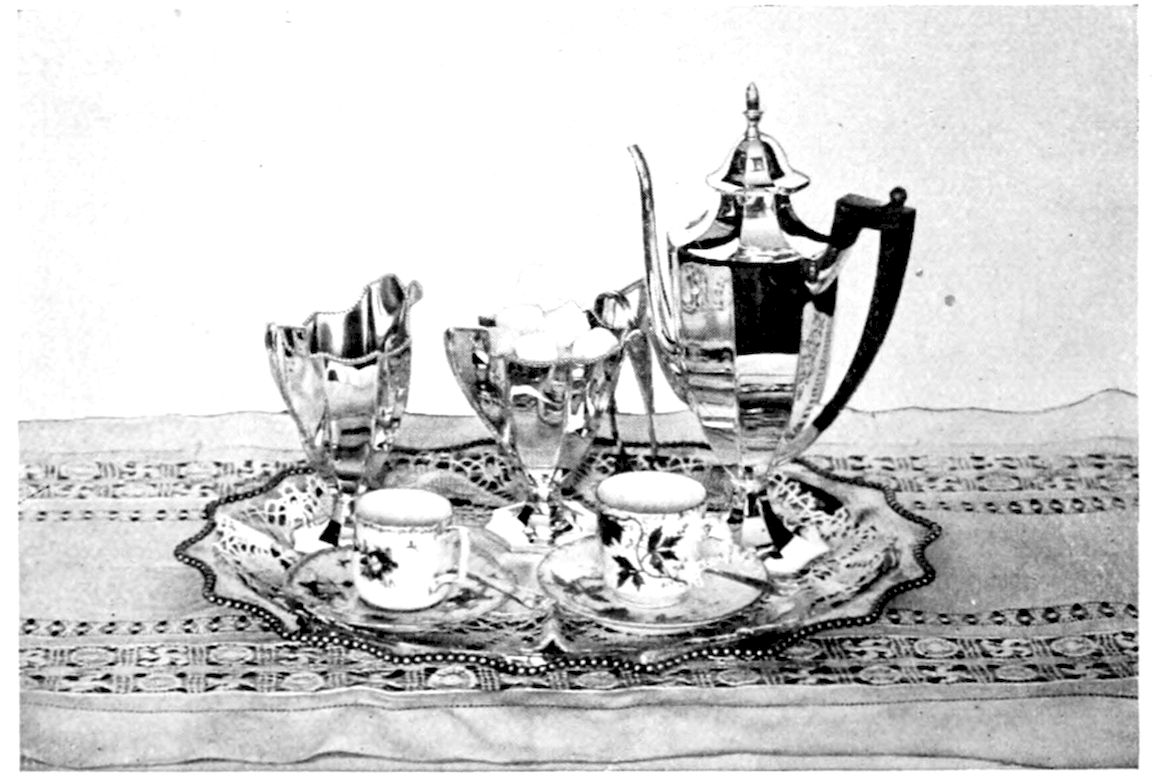After-Dinner Coffee Service. — A tall silver coffee-pot with a dark wooden handle, a cream jug, a sugar bowl of cut sugar, and two small china cups on saucers, on a tray laid with a lace doily.