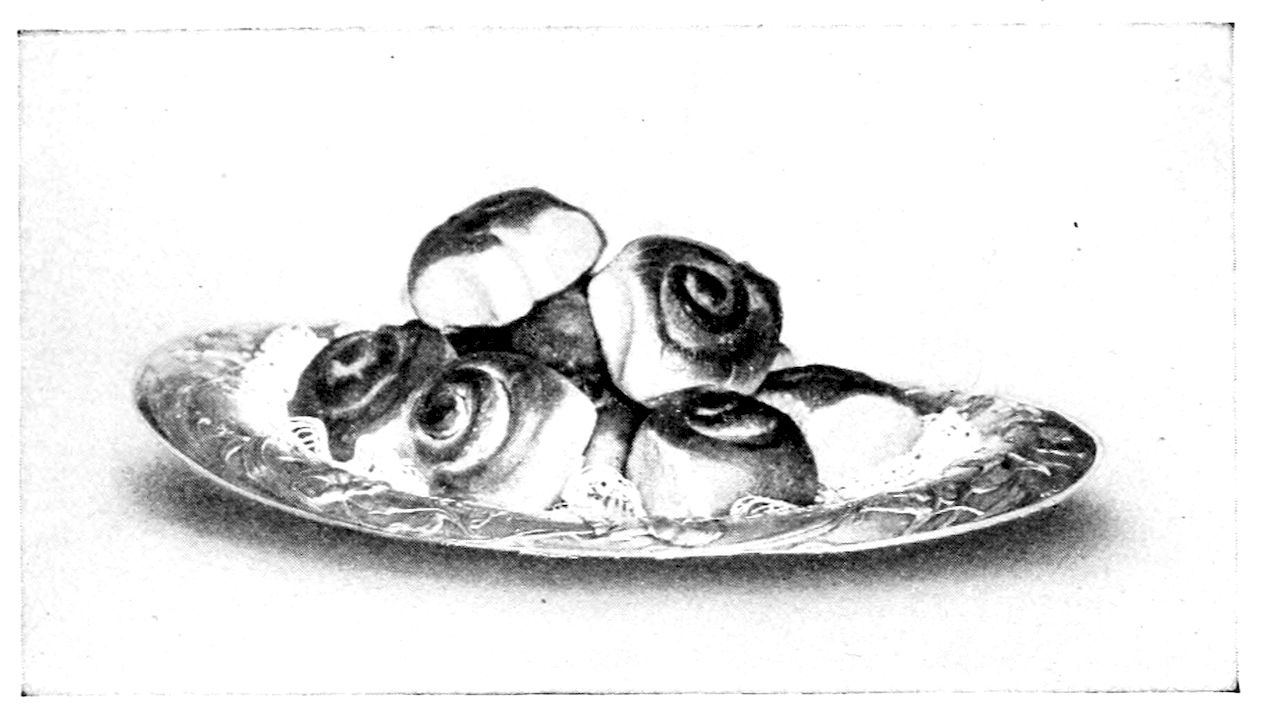 Sweet French Rolls. — Sweet French Rolls heaped on an oval dish: some rolled up like jelly rolls, showing the spiral on the cut side, and some plain, with a doily under them.