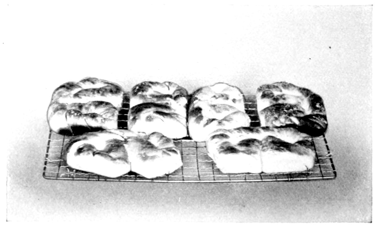 Coffee Cakes (Brioche). — Six twisted and coiled coffee cakes, glossy with icing, in two rows on a wire cake rack.