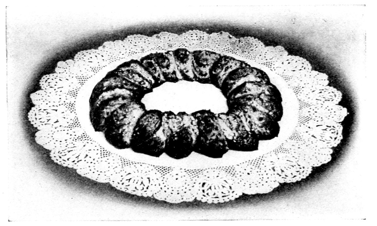 Swedish Tea Ring II. — The baked ring on a paper doily, its slices browned and opened out like the spokes of a wheel around an empty centre.