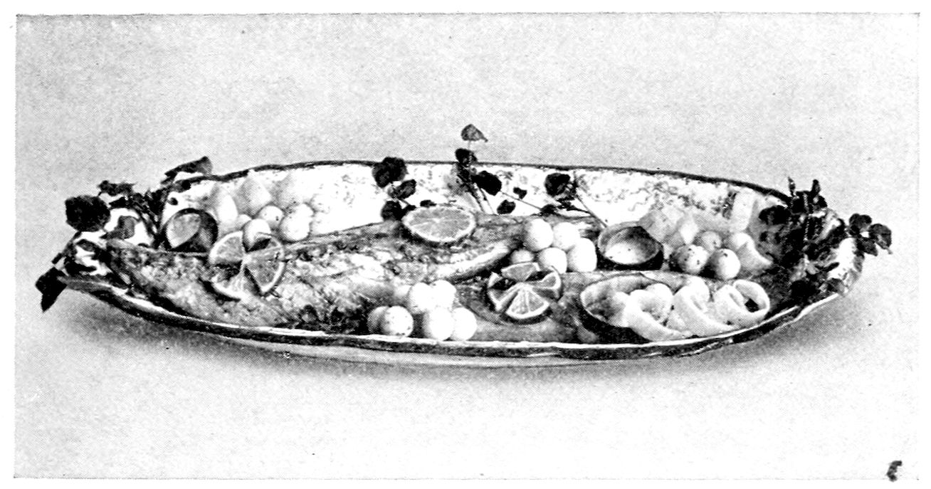 Boiled Mackerel, garnished with Potato Balls, Cucumber Ribbons Slices of Lemon cut in fancy shapes, and Parsley. — A whole mackerel on a long oval platter, surrounded by clusters of potato balls, lemon slices cut in fancy shapes, curled cucumber ribbons in a hollowed shell, and sprigs of green at both ends.