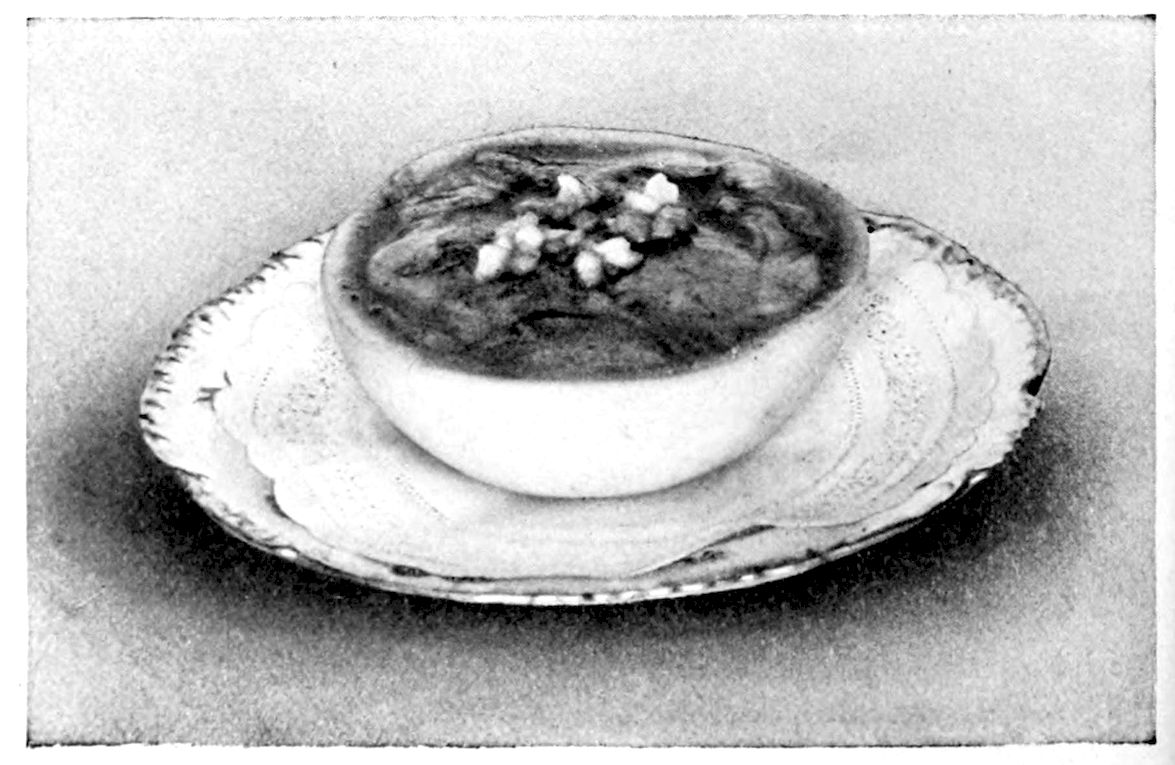 Oyster Cocktail II. — A grapefruit half, its rind smooth as a bowl, holds the seasoned oysters in its hollowed pulp with a little white garnish in the centre, and stands on a lace doily on a plate.