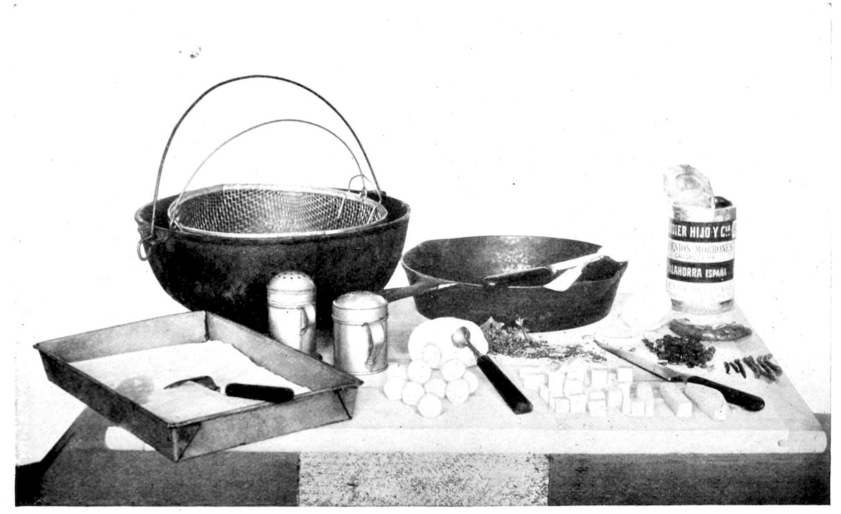 O’Brion Potatoes. — The makings rather than the dish: a frying kettle with wire basket, a frying-pan, salt and pepper shakers, a paper-lined pan, potato balls and cubes, chopped parsley and a tin of pimentoes.