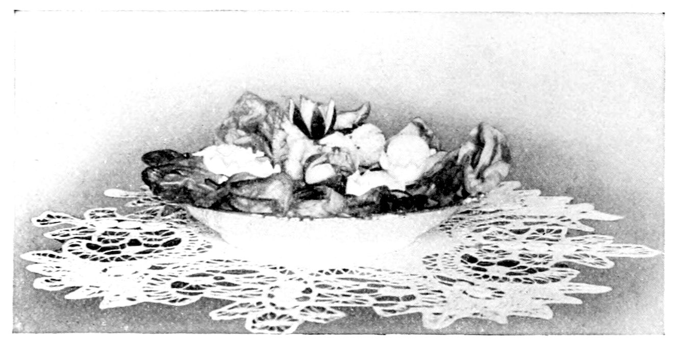 Egg Salad. — Stuffed egg halves nestle among lettuce leaves in a shallow white bowl set on a lace doily, one at the top cut into points like a flower.