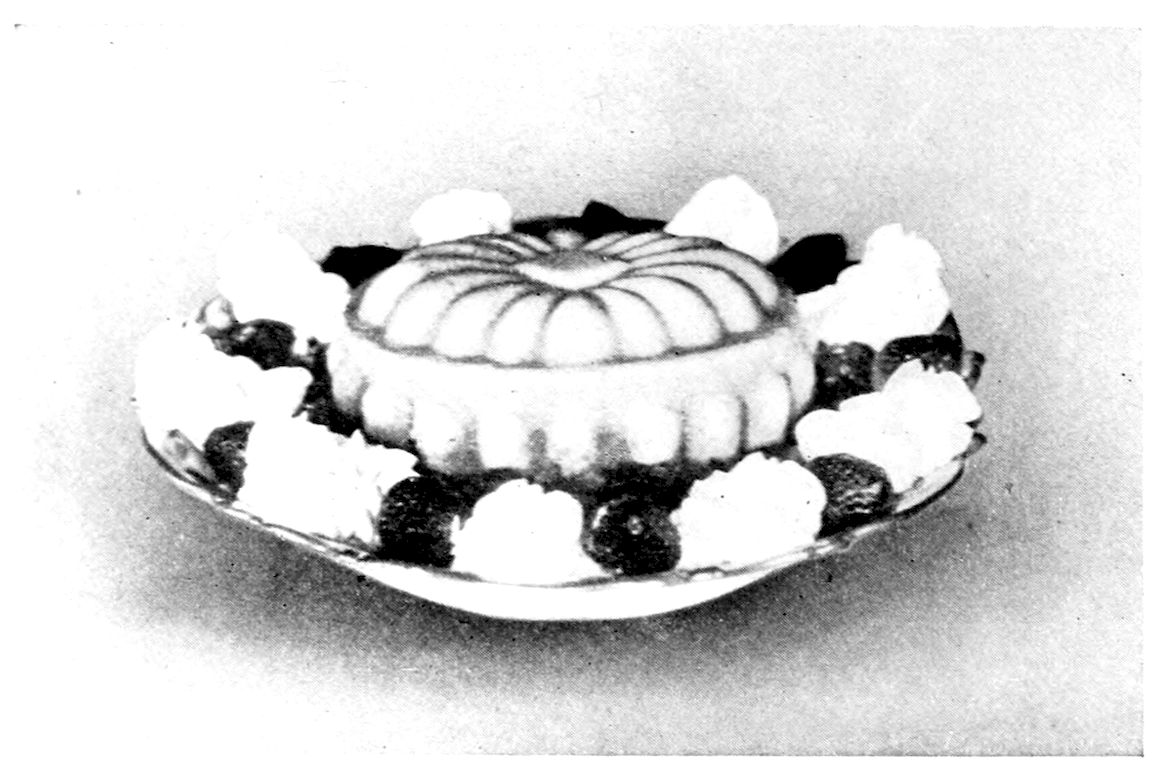 Harvard Pudding served with Crushed Berries and Whipped Cream. — A round pudding turned from a fluted mould, its top ridged like a melon, sits on a plate ringed with alternating mounds of whipped cream and whole berries.