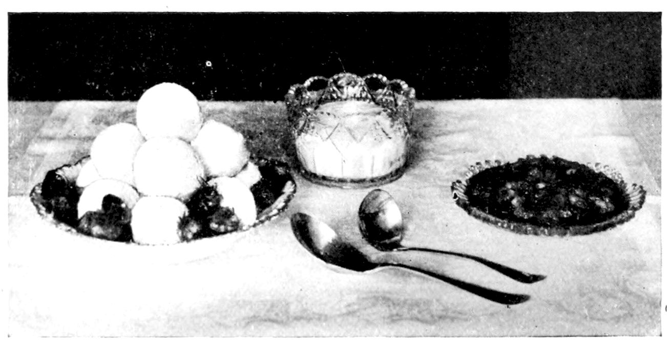 Snowballs garnished with Strawberries and served with Crushed Strawberries and Whipped Cream. — A pyramid of round white puddings on a cut-glass dish ringed with strawberries, beside a glass bowl of whipped cream, a dish of crushed berries and two serving spoons.