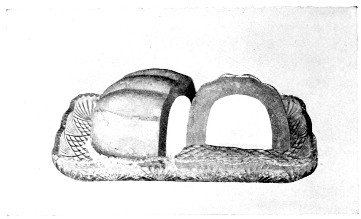 Bombe Glacée. — A melon-shaped mould turned out on a cut-glass tray, with one end cut away as an upright slice to show the darker lining around a pale hollow centre.