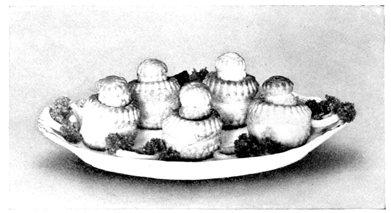 Patties Garnished with pastry rings and parsley. — Five tall, ridged puff-paste patty shells, each with a small round cover on top, stand on an oval platter with sprigs of parsley tucked around their bases.