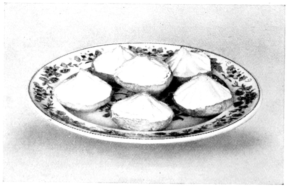 Lemon Tartlets. — Six tart cases heaped with meringue drawn up into points and lightly browned, arranged on a round plate with a flowered border.