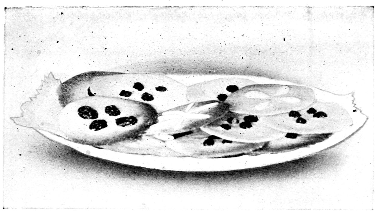 Rich Cookies. — Thin round cookies, most with four raisins pressed into the top and one or two with strips of almond, overlap on an oval plate edged with a paper doily.