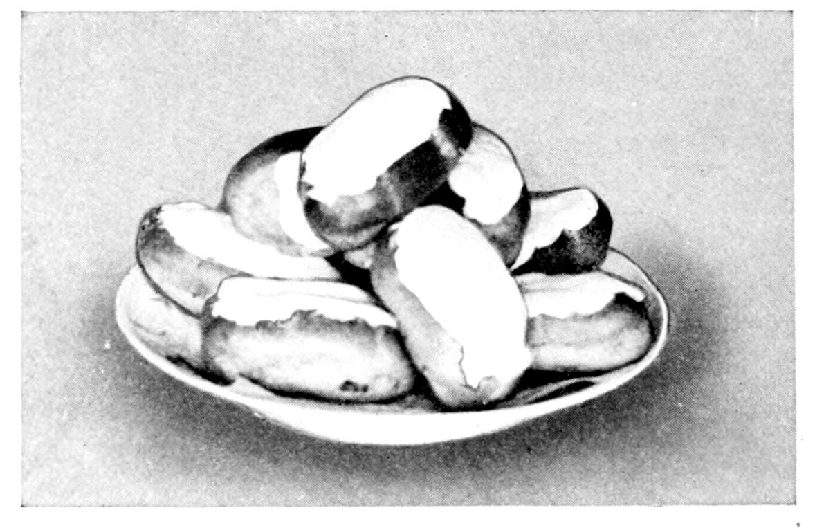Small Éclairs. — A shallow dish is piled with small éclairs, short plump fingers of pastry each dipped along the top in white frosting.