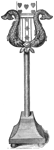 Fig. 44. — The card-case for the rising cards: an open lyre formed of two carved dolphins, on a tall pillar with a square plinth, the pack standing upright inside it with the top cards showing above.