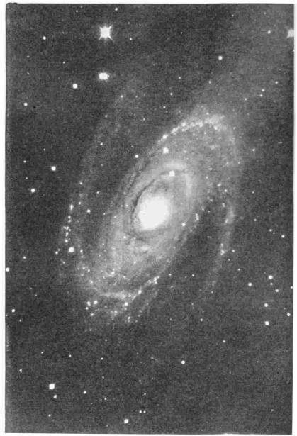 “Luminous Spiral Clouds of Matter” (Nebula photographed 1910) Photo: G. W. Ritchey — A photograph of a spiral nebula seen at a slant — a bright central nucleus wound about by arms of glowing matter studded with knots of light, against a field of scattered stars.