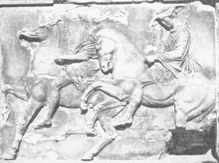 Part of the Famous Frieze of the Parthenon, Athens. A specimen of Grecian sculpture in its finest expression. Compare the advance of art with that seen in the animals on the archaic amphora in Chapter XIX. Photo: Fred Boissonnas — A marble relief of two young horsemen riding side by side to the left on rearing, high-stepping horses, the rider on the right wearing a helmet.