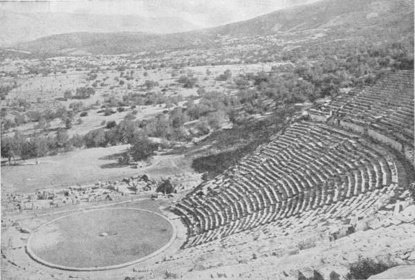 The Theatre at Epidauros, Greece. A wonderfully preserved specimen showing the vast auditorium. Photo: Fred Boissonnas — The great curved sweep of stone seats of the theatre rising up a hillside, around the round, flat floor of the stage, with olive groves and hills beyond.