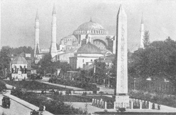 The Church (Now a Mosque) of S. Sophia, Constantinople. The obelisk of Theodosius is in the foreground. Photo: Sebah & Foaillier — The great domed church with its minarets stands among trees, and in the foreground rises the tall carved obelisk on its pedestal inside a railing.