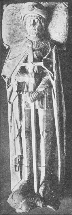 A Typical Crusader: Don Rodrigo De Cardenas. From the Church of S. Pedro at Ocana, Spain. (In the Victoria and Albert Museum) — A stone tomb effigy of a knight lying full length in armour under a long cloak, a cap on his head and a scallop shell above it, his hands resting on a great sword.