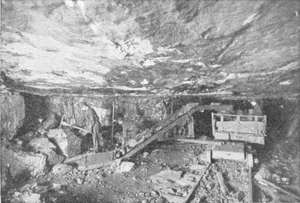Science in the Coal Mine. Portable Electric Loading Conveyor. Photo: Jeffrey Manufacturing Company, Columbus, Ohio — Miners work in a low underground seam, shovelling coal onto an inclined conveyor that loads it into a mine car standing on rails.