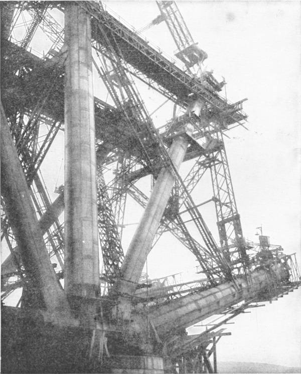 Constructional Detail of the Forth Bridge. Photo: Baker & Hurtzig — Great tubular steel legs and lattice girders of the bridge rise at steep angles, with cranes and scaffolding at work on the upper members.