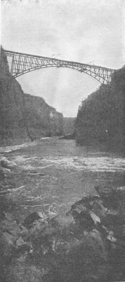 Railway Bridge Over the Gorge, Victoria Falls, of the Zambesi, Southern Rhodesia. Photo: British South African Co. — A single steel arch spans the narrow rock gorge high above the churning river below.