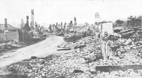 The Ruins of Ypres (Once a Delightful Old Flemish Town) To show the complete destructiveness of modern war. Photo: Topical — A road runs between heaps of rubble and broken walls, with only a line of bare chimney stacks and gutted houses left standing.