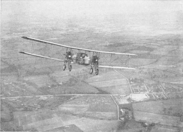 Passenger Aeroplane Flying Over Northolt. (Photo taken from another ’plane by the Central Aerophoto Co.) — A large biplane with two engines flies over a patchwork of fields, roads and buildings far below.