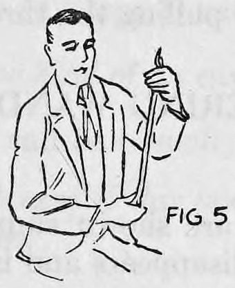 Fig. 5. — A seated spectator in a suit holds the wrapped wand upright, one hand at the top end and the other at the bottom end.