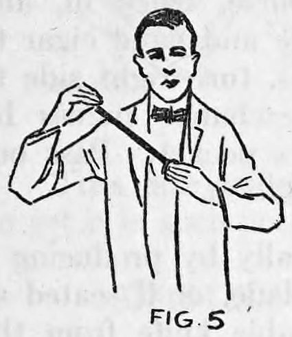 Fig. 5. — A smiling man in a suit holds the pocketbook at his chest in his left hand and draws the long wand out with his right hand.