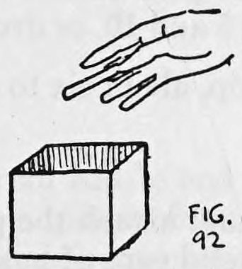 Fig. 92. — An open cardboard box seen from the side with the right hand, fingers together, held above it as if just dropping a cigarette in, the hand apparently empty.