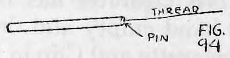 Fig. 94. — A cigarette lying sideways with the pin pushed into one end and the thread running off from the pin to the right.
