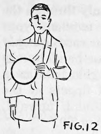 Fig. 12. — A man holds the tambourine of paper and hoops in front of him with his left hand, his right hand hanging at his side against the coat.