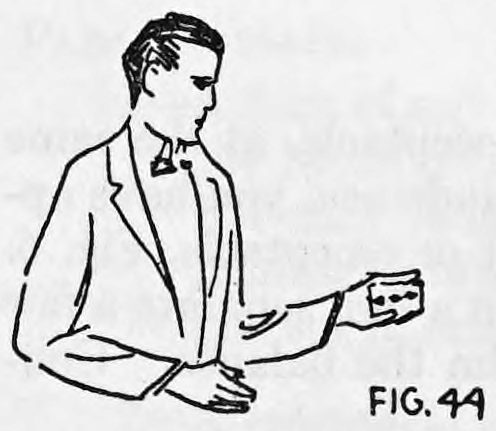 Fig. 44. — A man in a suit stands with his right side turned slightly towards the audience, holding a deck of cards out in his left hand.