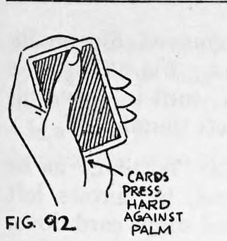 Fig. 92. — A left hand holds the deck with fingers curved upward, pressing the cards against the base of the thumb; a label reads cards press hard against palm.