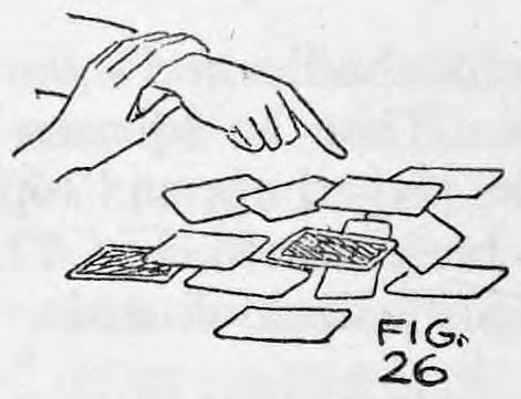 Fig. 26. — The performer's hand grasps the spectator's wrist and guides the spectator's pointing hand over cards scattered on the table.