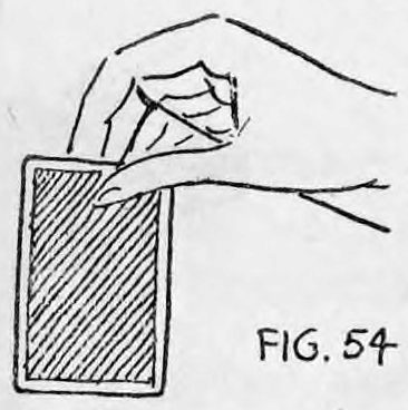 Fig. 54. — A hand seen from behind, away from the audience, gripping the upper edge of a playing card between thumb and finger, with the thread running off to the right.