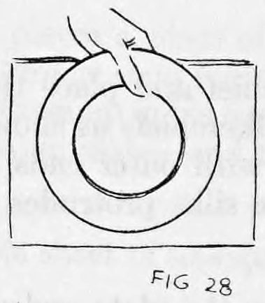 Fig. 28. — A plate held in the left hand against the newspaper, with the right hand's fingers showing it at the top edge.