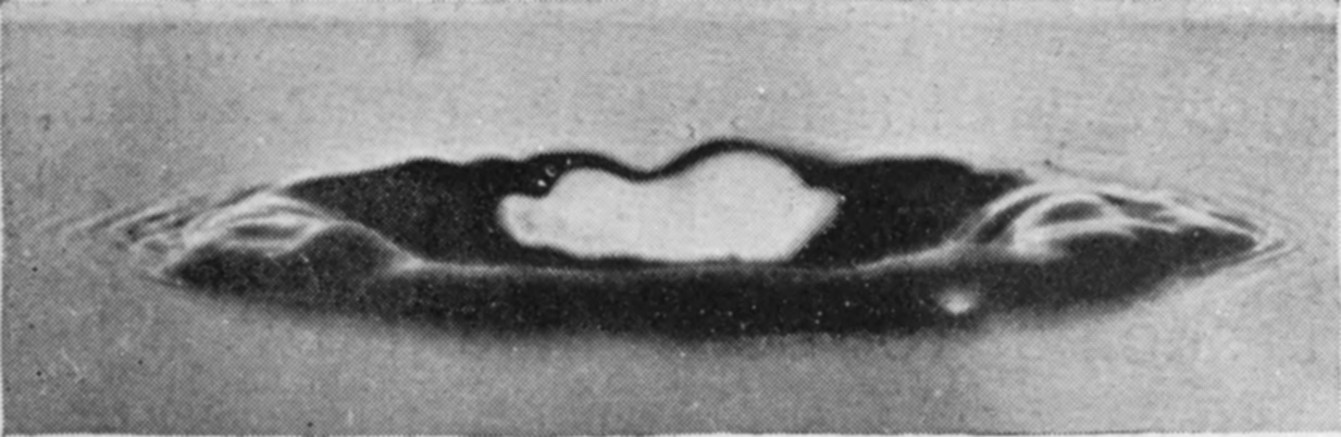 7 0·058 sec. — A thick central column is rising out of the middle of the flattened crater, while ripples spread outward across the surface on either side.