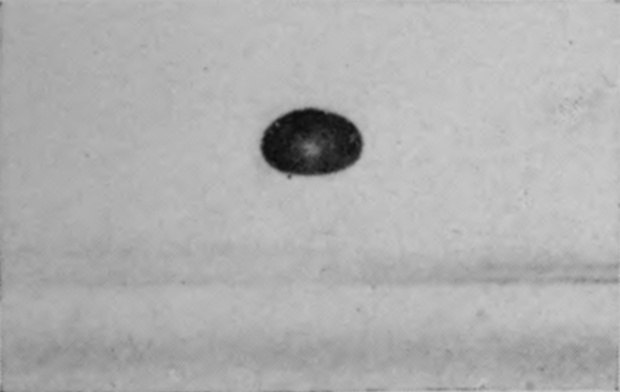 1 — The drop, slightly flattened, is still in the air just above the surface; the grey band across the picture is the region of confusion at the level of the water.