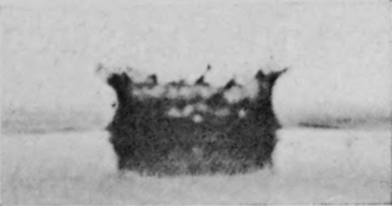 2 T = 0 — The drop has just entered: a shallow dark hollow has opened, and its rim is rising in a ragged frill of little jets.