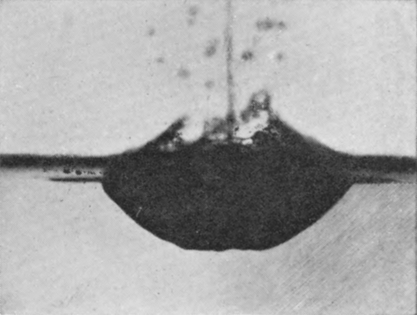 3 0·064 sec. — A thin jet has risen through the middle of the spent bubble, whose fragments hang about it as dark drops, above a broad shallow cavity.
