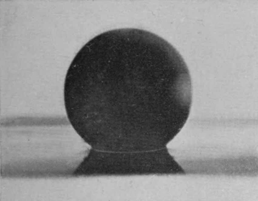 1 0·003 sec. — Lit from behind, the polished sphere is a dark silhouette just touching the surface, with a fine bright line at its base and its reflection beneath.