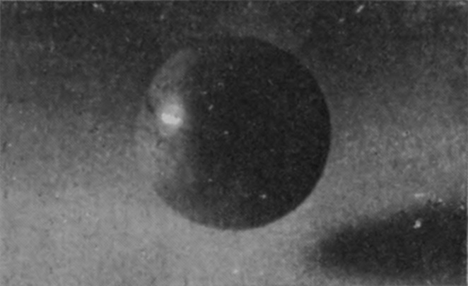 1 — The polished ivory sphere touches the milky water, and a thin film of liquid is just starting to climb its left side.