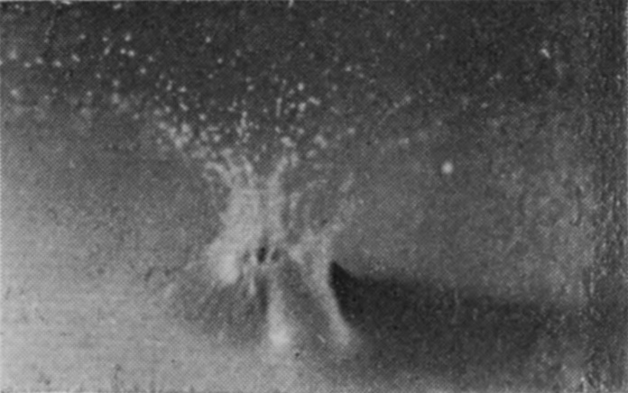 5 — The sphere is under, and the broken sheath closes in above it as converging jets that throw off a spray of droplets.